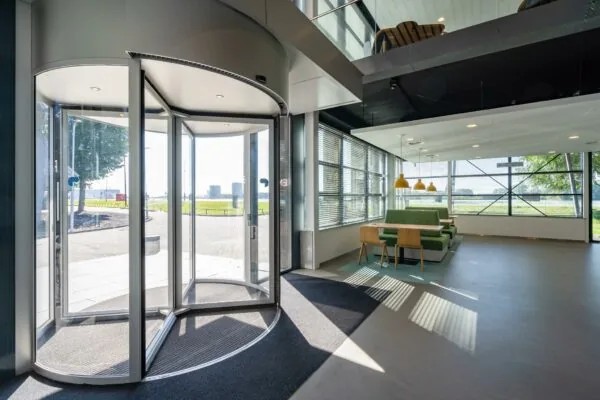 Licht en modern entreegebied van Rivium Promenade met draaideur en zithoek met groene bankjes.